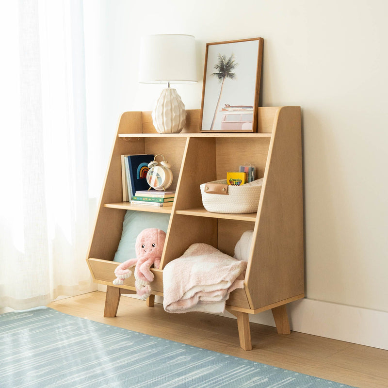 Wooden children's bookshelf and toy organizer in bright nursery with lamp, framed palm print, basket of crayons, books and pink plush octopus
