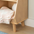 Light oak storage bench with tapered legs and neatly folded pink and white terry towels inside, placed on a hardwood floor in a minimalist interior.