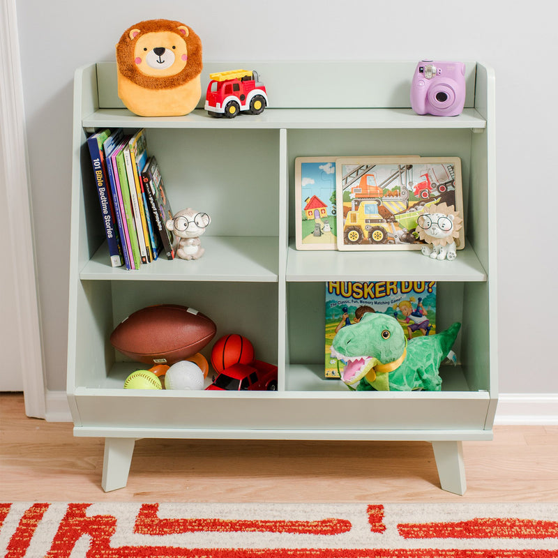Light green kids bookshelf toy organizer in a playroom filled with children's books and puzzles, plush lion and dinosaur, toy fire truck, purple camera, football and balls