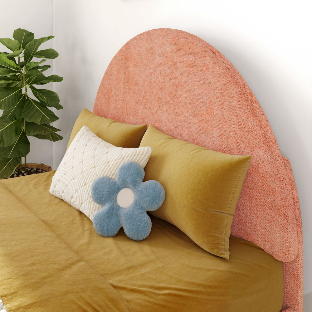 Cozy bedroom with textured peach headboard, mustard bedding, decorative white and blue pillows, and indoor plant.
