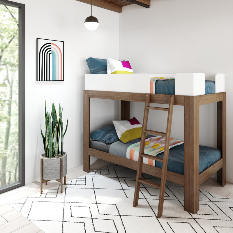 Modern wooden twin bunk bed in minimalist kids' bedroom with colorful pillows, geometric rug, framed rainbow art and potted snake plant