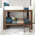 Modern wooden bunk bed with ladder, white top guardrail and colorful pillows and blankets in a bright kids' bedroom with patterned rug.