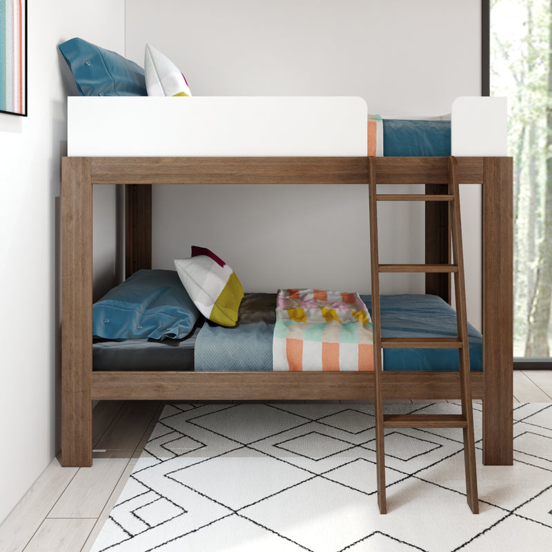 Modern wooden bunk bed with ladder, white top guardrail and colorful pillows and blankets in a bright kids' bedroom with patterned rug.