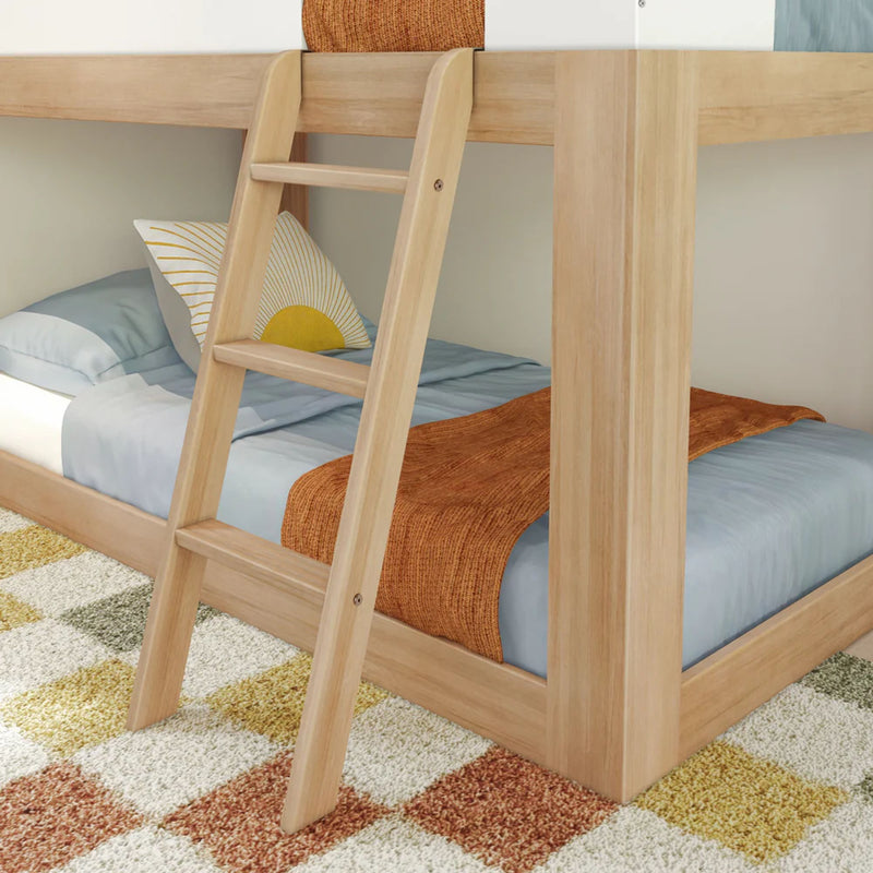 Modern wooden bunk bed with blue bedding, orange throw blanket, and decorative pillow in a cozy room with checkered carpet.