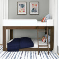 Modern wooden bunk bed with ladder, navy quilted bedding on lower bunk, colorful patterned throw pillows, abstract framed wall art, gray wall, white curtains and striped rug in a kids' bedroom
