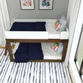 Twin-over-twin wooden bunk bed with white frame and navy quilts, colorful striped and blue patterned pillows, abstract framed wall art and striped rug in a modern kids' bedroom