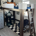Modern wooden loft bed with ladder and white guardrails, navy bedding and leather accent pillows above a bookshelf, black-and-white geometric wall mural and checkerboard rug in kids' bedroom