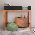 Wooden loft bed with ladder and black safety rail over a wooden dresser, green bean bag on patterned rug, striped pillow, books and headphones—modern kids bedroom setup