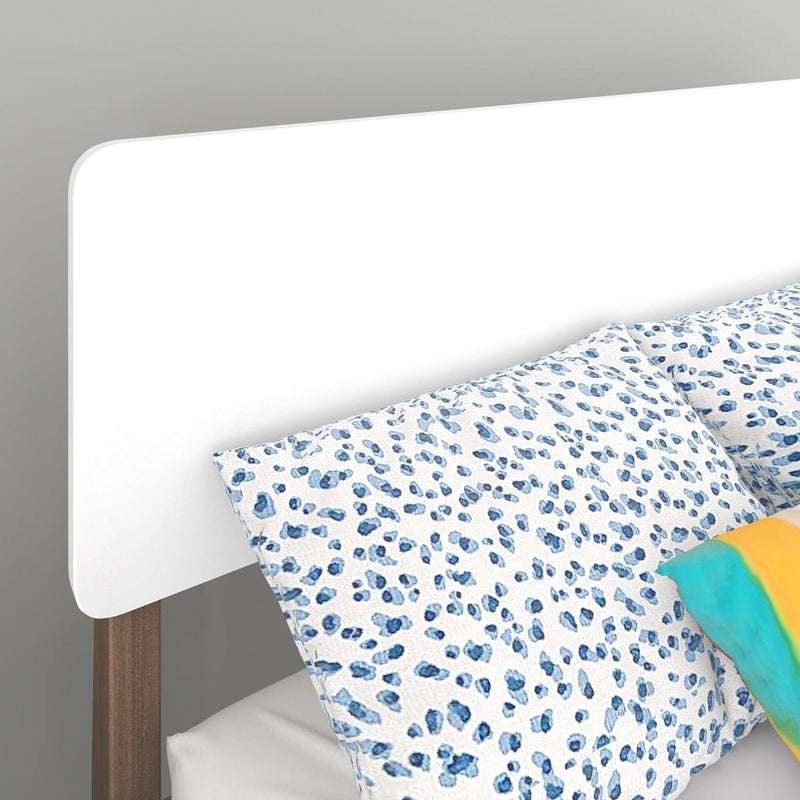 Modern white headboard with blue leopard print pillows and colorful accessories on a stylish bed.