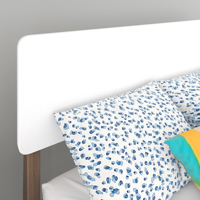 Close-up of modern white rounded headboard with wooden legs and blue spotted leopard-print pillow and bedding
