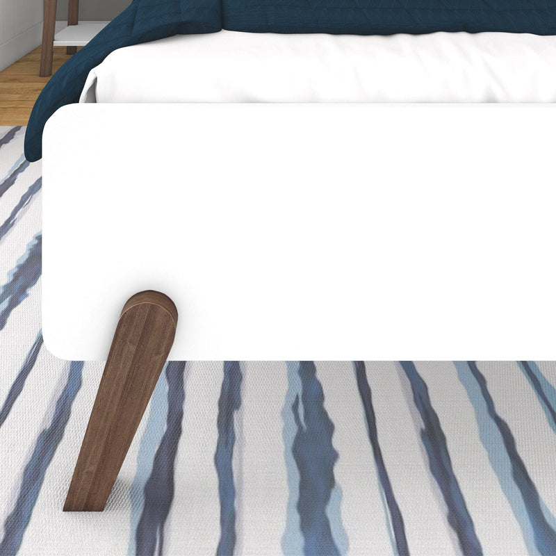 Modern minimalist bed frame with wooden leg detail on striped carpet.