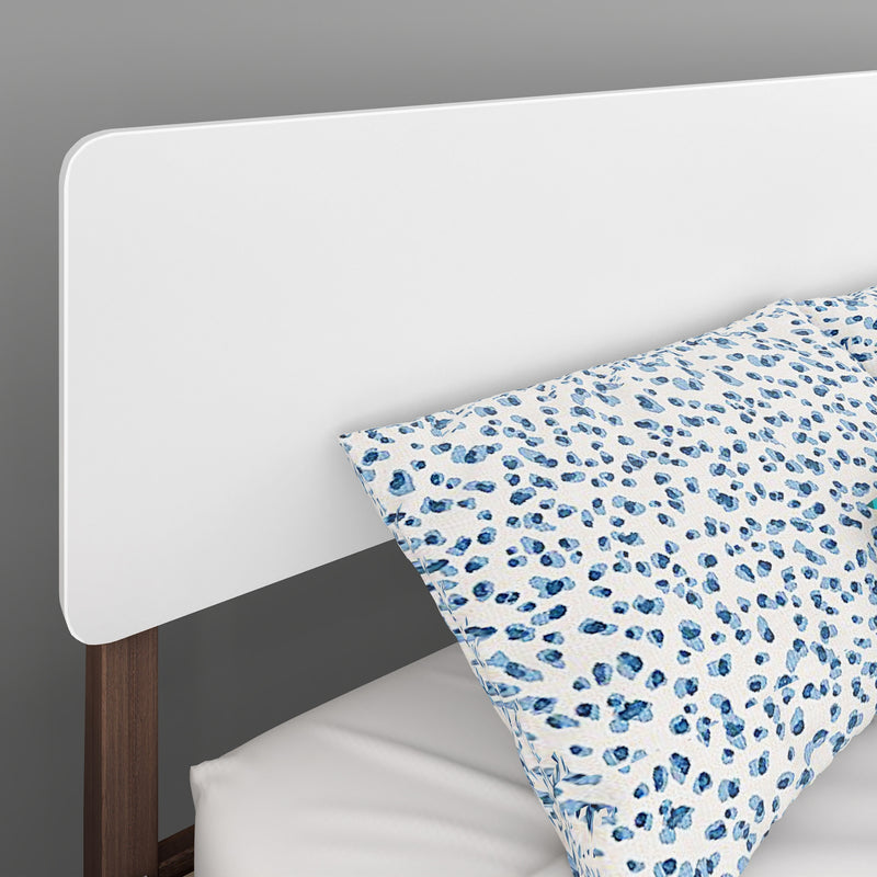 Modern white headboard with walnut legs and blue leopard-print pillowcase on gray bedroom backdrop