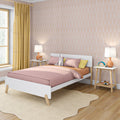 Modern Scandinavian children's bedroom with white platform bed, pink bedding, pastel arched wallpaper, yellow curtains, wooden nightstands and stuffed rabbit