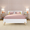 Modern kids bedroom with white mid-century bed, pink bedding, stuffed rabbit, pastel arch wallpaper, wooden nightstands with ceramic lamps, cozy nursery decor