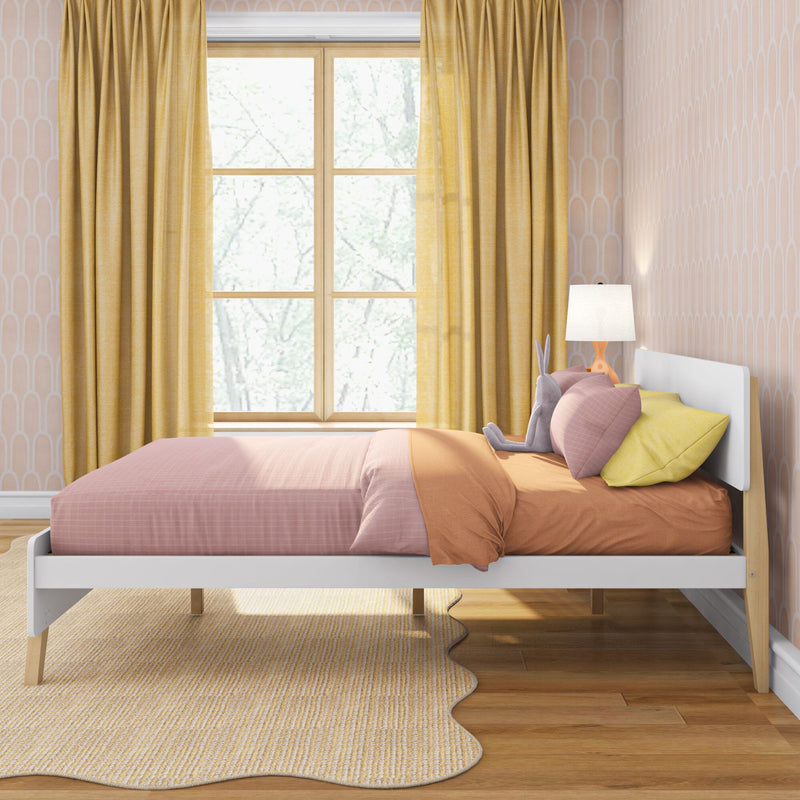 Modern kids bedroom with white platform bed, pink and orange bedding, yellow curtains, plush bunny on pillows, bedside lamp, scalloped rug and large window with tree view