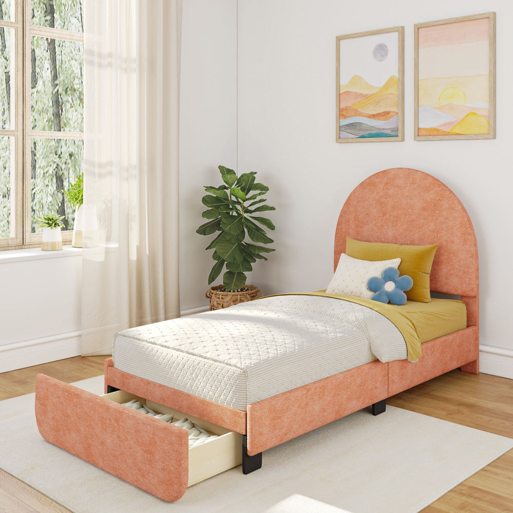 Single bed with orange fabric headboard and pull-out storage drawer in a sunlit bedroom with potted plant and abstract artwork.