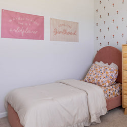 Cozy children's bedroom with pink canopy bed, floral bedding, and motivational wall art.