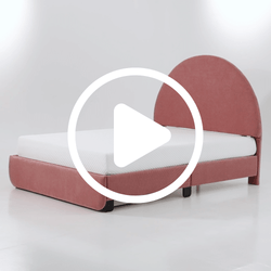 Modern pink upholstered platform bed with rounded headboard and white mattress in minimalist studio setting