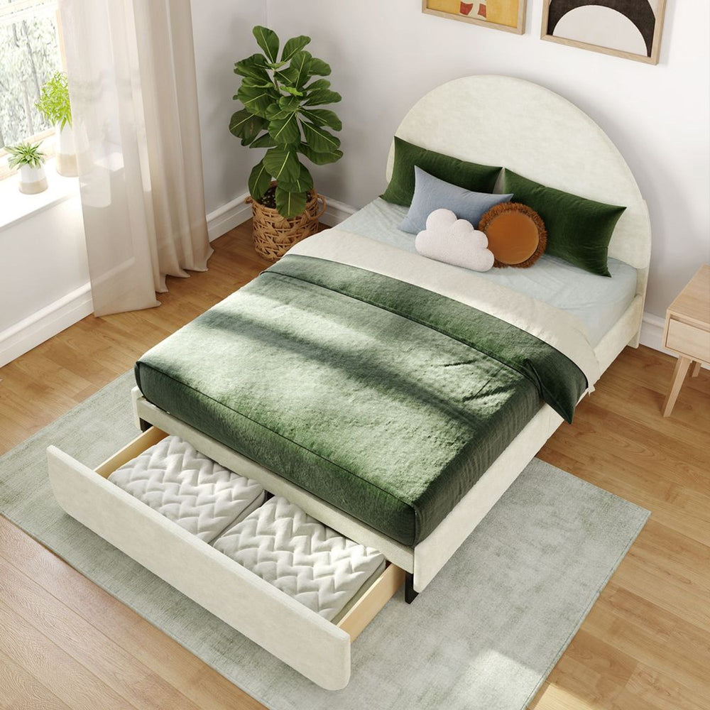 Wooden bed with green bedding, under-bed storage drawer, and indoor plant in a bright minimalist bedroom.