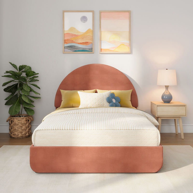 Cozy modern bedroom with rust-colored upholstered headboard, neutral striped bedding and yellow accent pillows, blue flower plush, two framed pastel landscape prints above the bed, woven basket fiddle-leaf fig plant and ceramic bedside lamp on a wooden nightstand