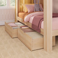 Wooden canopy kids bed with pink bedding, plush bunny toy and under-bed storage drawers filled with folded blankets