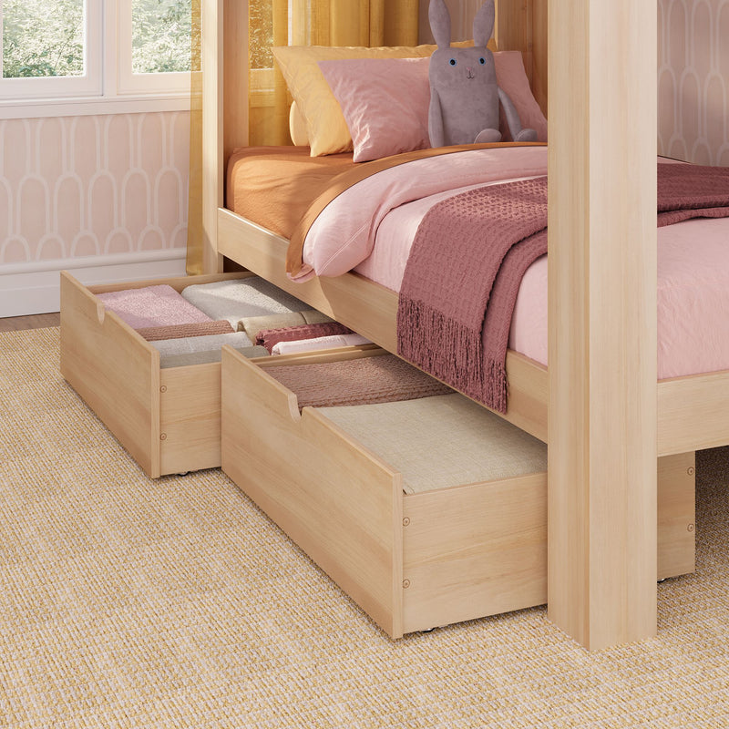 Wooden canopy kids bed with pink bedding, plush bunny toy and under-bed storage drawers filled with folded blankets