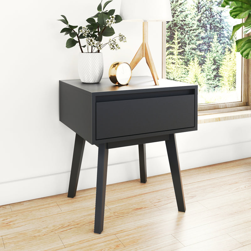 Modern black nightstand with a vase, clock, and lamp near a sunny window.