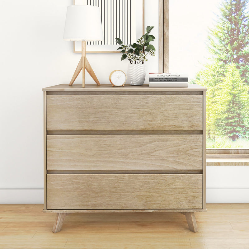 Minimalist light oak mid-century modern three-drawer dresser for bedroom storage, styled with table lamp, potted plant, clock and books by a sunny window