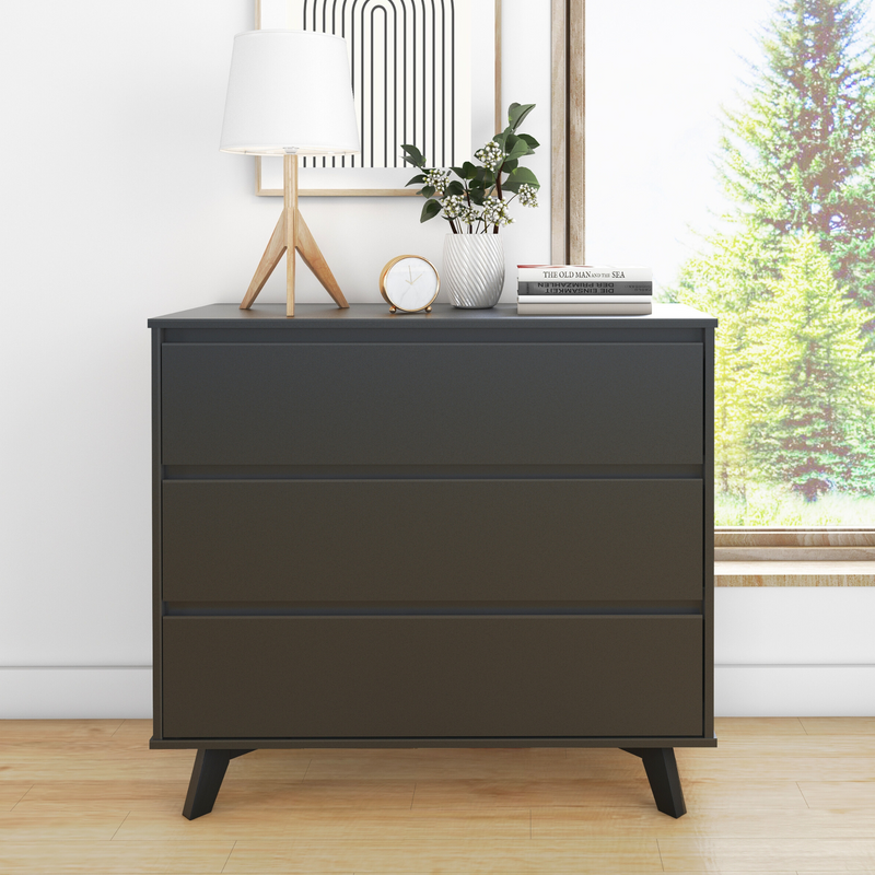 Modern black dresser with three drawers, featuring a stylish lamp and decor, positioned near a large window with a scenic outdoor view.