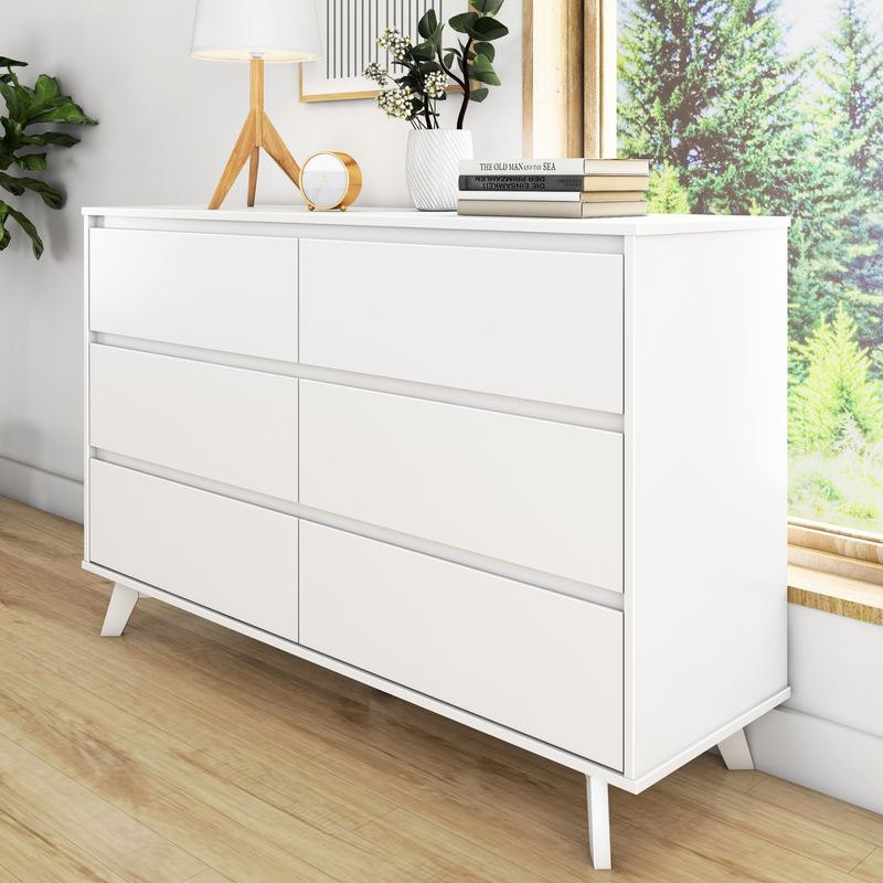 White six-drawer dresser in modern bedroom with wooden floor and decorative items.