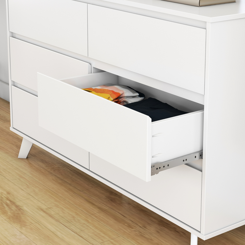 White modern dresser with open drawer revealing neatly folded clothes on wooden floor.