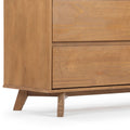 Close-up of a mid-century modern wooden dresser corner with tapered legs and natural oak wood grain, bedroom furniture detail