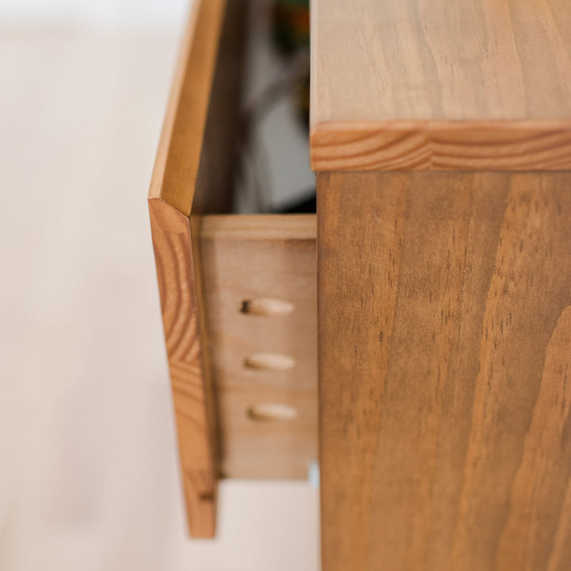 Close-up of an open solid wood dresser drawer with visible wooden dowel joinery and natural wood finish, furniture detail