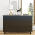 Modern black six-drawer dresser with mid-century legs, styled with a wooden tripod lamp, potted plant, clock and stacked books by a sunny window, minimalist bedroom decor