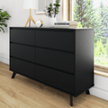 Modern matte black six-drawer dresser with angled legs and sleek handleless design for bedroom storage, styled with lamp and books by a sunlit window