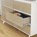 Mid-century modern light wood dresser with open drawer showing folded clothes, bedroom storage on hardwood floor