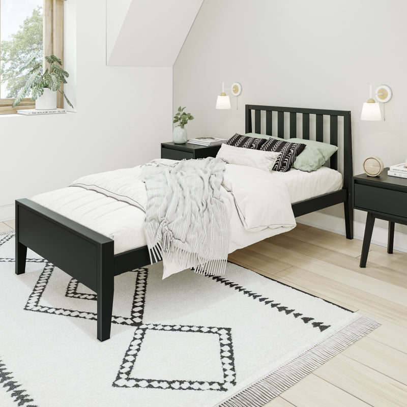 Modern minimalist bedroom with a black wooden bed frame, white bedding and throw, geometric black-and-white rug, matching black nightstands, wall sconces, light wood floor and potted plant by the window