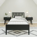 Modern minimalist Scandinavian bedroom with black wooden bed frame, matching nightstands, neutral white bedding, patterned rug, wall sconces and potted plant