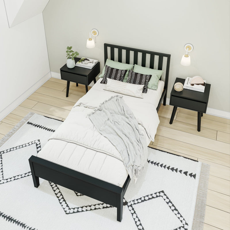 Stylish minimalist bedroom with black bed, white bedding, matching nightstands, and geometric rug.