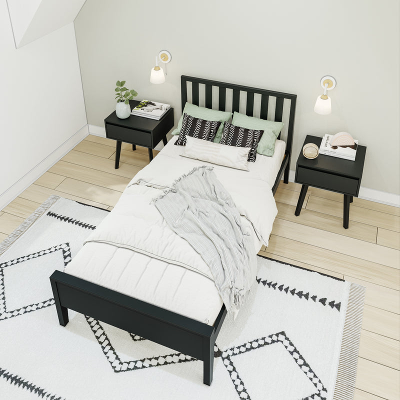 Modern minimalist Scandinavian bedroom with black wooden bed, matching nightstands, wall sconces, soft green pillows and patterned rug on light hardwood floor
