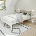 Modern minimalist Scandinavian bedroom interior with white platform bed, neutral linen bedding, green accent pillows, patterned rug, wooden floor, bedside tables, wall sconces and indoor plants