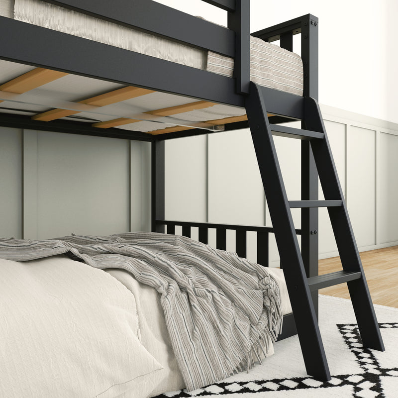 Modern black metal bunk bed with ladder in minimalist bedroom design, featuring cozy bedding and a stylish striped rug.