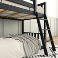 Modern black metal loft bunk bed with ladder and wooden slats, lower bed with beige linens and gray striped throw in a bright minimalist bedroom