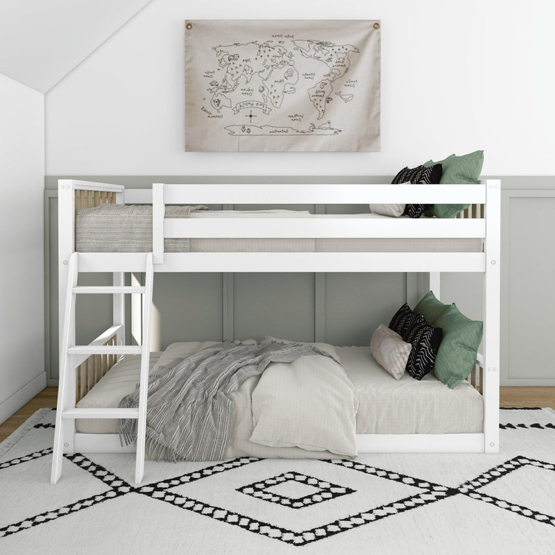 Space-saving white wooden bunk bed with ladder in modern neutral kids' bedroom, lower bed styled with green and black pillows, gray throw blanket, world map wall art, and black-and-white geometric rug