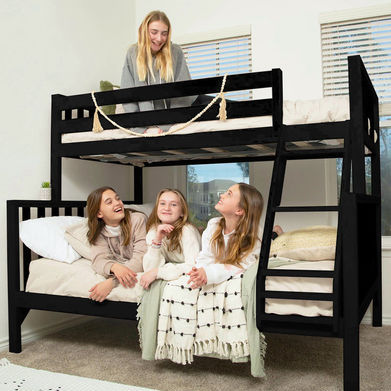 Black wooden twin-over-full bunk bed with ladder and neutral bedding in a bright kids' bedroom, four smiling children lounging on top and bottom bunks