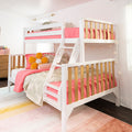 White wooden bunk bed with ladder and pink bedding in a styled kids' bedroom with orange flower pillow and string lights