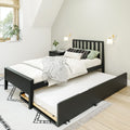Minimal Scandinavian bedroom with black wooden trundle bed, white bedding, black-and-white patterned pillows and rug, wall sconces and potted plant by sunlit window