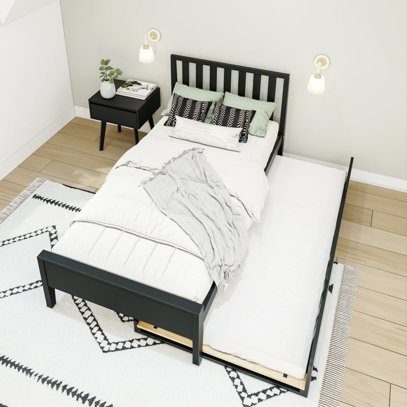 Modern minimalist bedroom with black platform bed and pull-out trundle, white bedding, black nightstand, wall sconces, light wood floor and patterned rug