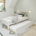 Minimalist Scandinavian bedroom with white wooden trundle bed, neutral layered bedding, wall sconces, potted plant and natural light