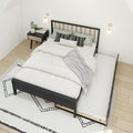 Modern Scandinavian bedroom featuring a black wood trundle bed with white bedding and a gray throw, green and patterned accent pillows, wood-and-black nightstand with plant and magazines, wall-mounted sconces and geometric rug on light hardwood floor.